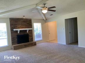 Lewisville house for rent - an empty living room with a brick fireplace and a ceiling fan