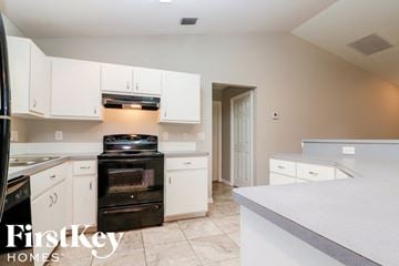Fort Myers house for rent - A kitchen with a black stove top oven and white cabinets.