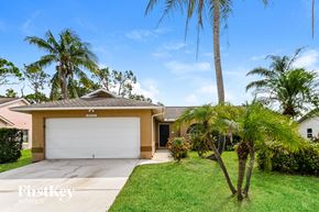 Fort Myers house for rent - a home with palm trees and a driveway and a garage door