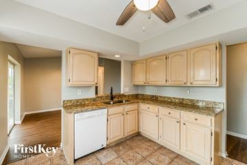 Fort Myers house for rent - a kitchen with white cabinets and granite counter tops