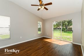 Fort Myers house for rent - a living room with wood floors and a large window and a ceiling fan