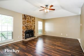 Cypress house for rent - A spacious room with a stone fireplace and wooden flooring.
