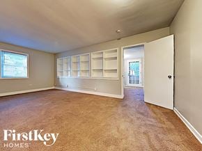 Homewood house for rent - an empty living room with white shelves and a door to a hallway