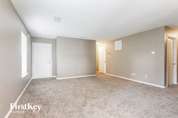 Indianapolis house for rent - a spacious living room with carpet and a door to a bedroom