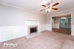 Loganville house for rent - A well-lit room with a fireplace and a ceiling fan.