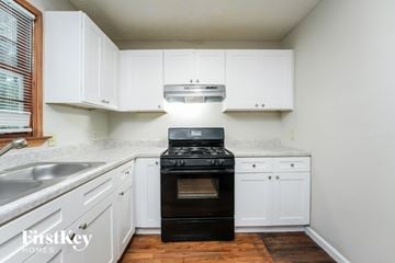 Loganville house for rent - A kitchen with white cabinets and a black stove top oven.