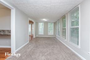 Loganville house for rent - A spacious room with a carpeted floor and a fireplace on the left side.