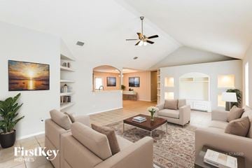 Katy house for rent - A living room with a beige couch and a painting of a sunset on the wall.