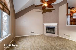 Liberty house for rent - an empty living room with a fireplace and a ceiling fan