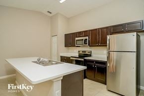 Port St. Lucie house for rent - A kitchen with a stainless steel refrigerator, microwave, and oven.