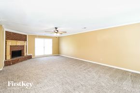 Cordova house for rent - a empty living room with a brick fireplace and a ceiling fan