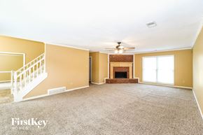 Cordova house for rent - a carpeted living room with a fireplace and a ceiling fan