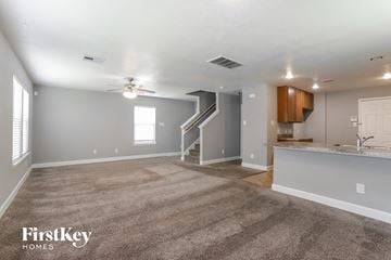 Houston house for rent - a living room with carpet and a kitchen with a ceiling fan