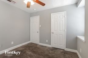 Houston house for rent - a bedroom with two doors and a carpeted floor and a ceiling fan