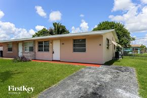 North Lauderdale house for rent - a small pink house with a lawn and a driveway