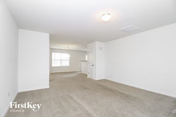Whitsett house for rent - a spacious living room with carpet and white walls