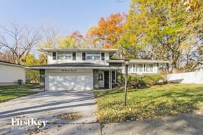 Lansing house for rent - a white house with a driveway and a garage door