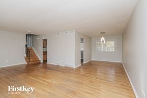 Lansing house for rent - an empty living room with a hard wood floor and a staircase