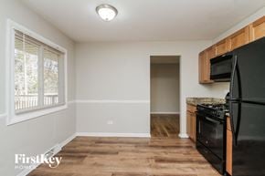 Lansing house for rent - an empty kitchen with black appliances and wood flooring