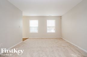 Noblesville house for rent - a spacious living room with carpet and two windows