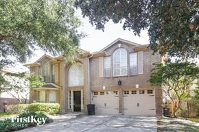 Katy house for rent - A house with a garage is surrounded by trees.