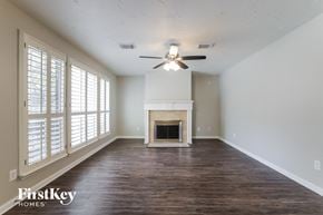 Katy house for rent - A spacious room with a fireplace and a ceiling fan.