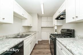 Lithonia house for rent - a kitchen with white cabinets and granite counter tops and a black stove
