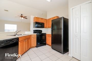 Cape Coral house for rent - A kitchen with wooden cabinets and black appliances.