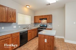 Houston house for rent - a kitchen with wooden cabinets and a black dishwasher and a sink