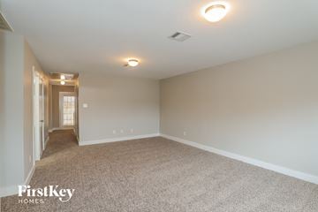 Houston house for rent - a spacious living room with carpet and a door to a hallway