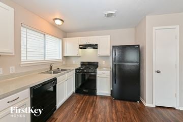 Houston house for rent - A kitchen with a black fridge and white cabinets.