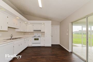 North Port house for rent - a kitchen with white cabinets and white appliances and a sliding glass door