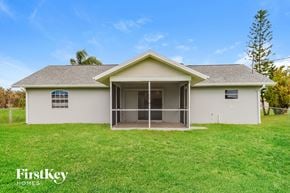 North Port house for rent - a white house with a screened porch and a grass yard
