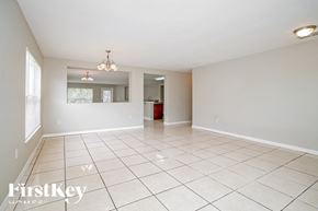Poinciana house for rent - A spacious room with white tiled flooring and a chandelier hanging from the ceiling.