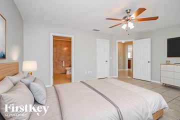 Poinciana house for rent - A bedroom with a large bed and a ceiling fan.