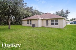 Poinciana house for rent - A small house with a brown roof is surrounded by a grassy lawn.