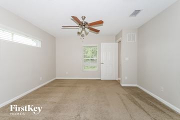 Port St. Lucie house for rent - a spacious living room with carpet and a ceiling fan