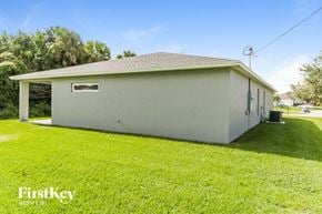 Port St. Lucie house for rent - the front of a white house with a yard and grass