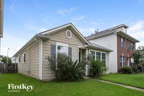 Houston house for rent - A house with a beige siding and a red brick house in the background.
