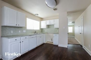 Houston house for rent - A kitchen with white cabinets and a wooden floor.
