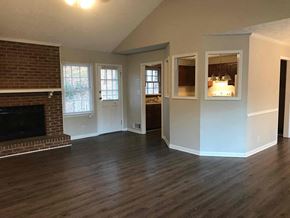 Snellville house for rent - an empty living room with a brick fireplace and wooden floors