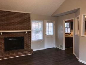 Snellville house for rent - a living room with a brick fireplace and a door to a bathroom
