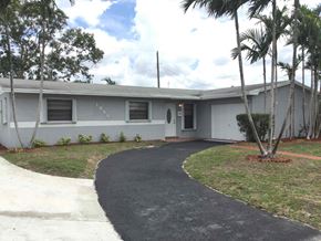 Miami Gardens house for rent - the front of a white house with a driveway and palm trees
