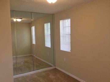 Miami Gardens house for rent - a bedroom with a mirrored closet and a carpeted floor