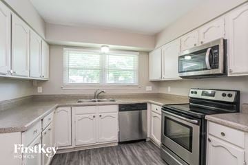 Humble house for rent - a kitchen with white cabinets and stainless steel appliances