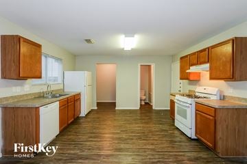 Cypress house for rent - A kitchen with wooden cabinets and a white fridge.