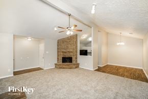 Cypress house for rent - a living room with a fireplace and a ceiling fan