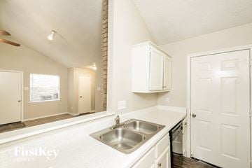 Cypress house for rent - a kitchen with white cabinets and a sink and a window