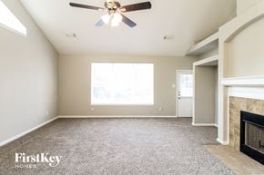Katy house for rent - an empty living room with a ceiling fan and a fireplace