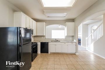 Katy house for rent - a kitchen with black appliances and white cabinets